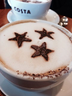 Close-up of a cappuccino with three cocoa powder stars on the foam