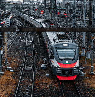 Modern electric passenger train on railway tracks at junction with overhead lines and signal equipment