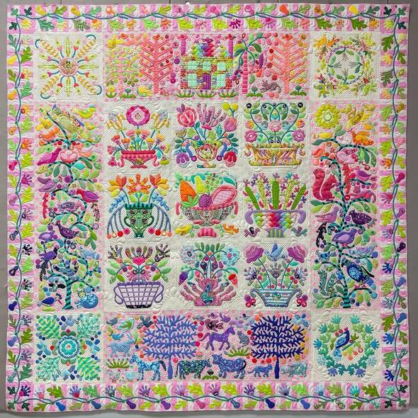 Colorful handmade quilt with floral basket blocks in pink, blue, yellow and green arranged in a grid pattern