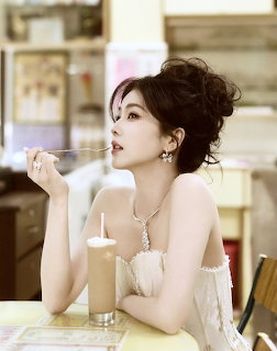 Woman in white dress sitting at cafe table holding spoon