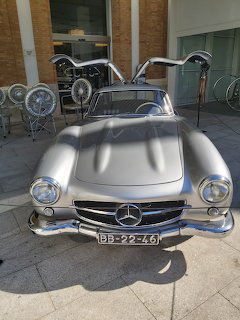 Silver Mercedes-Benz 300SL Gullwing classic car with open gullwing doors in a showroom