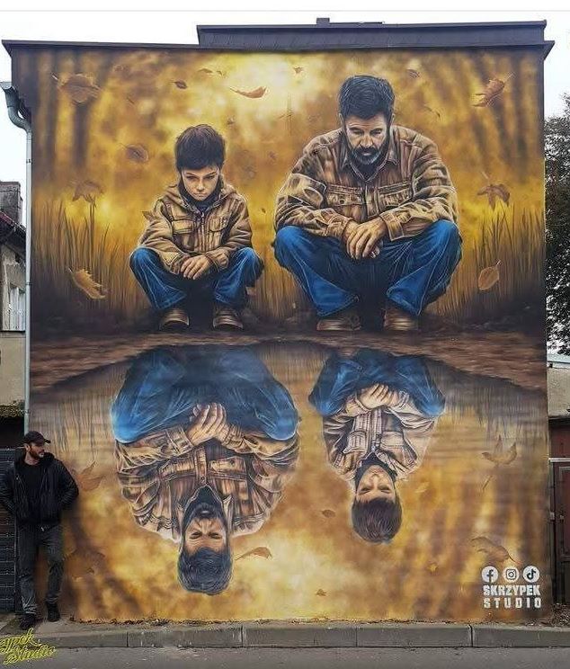 Street art mural of a father and son crouching with their reflection visible in water below, golden autumn tones