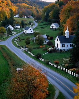 Aerial view of a New England village with white houses and church surrounded by colorful fall trees