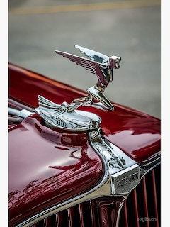 Chrome hood ornament on the hood of a red vintage Auburn car