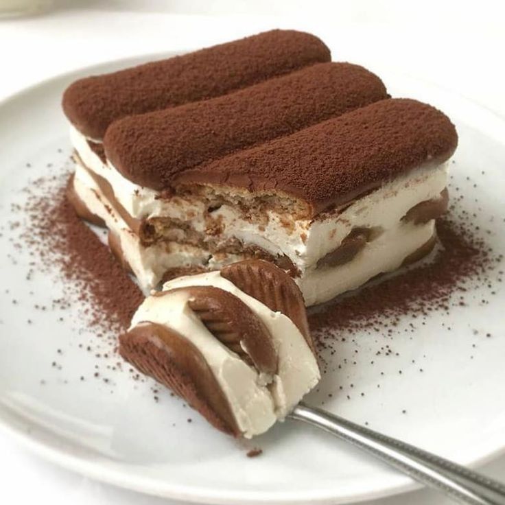 Slice of tiramisu dessert with cocoa powder topping and cream layers on white plate
