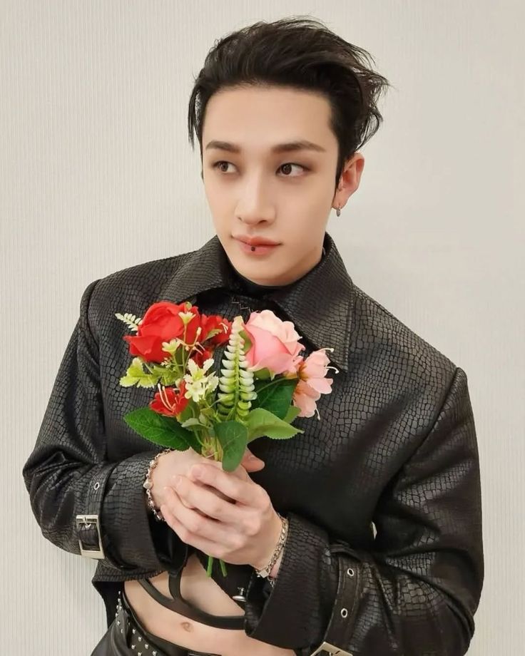 Young Asian man in black leather jacket holding a red and pink flower bouquet