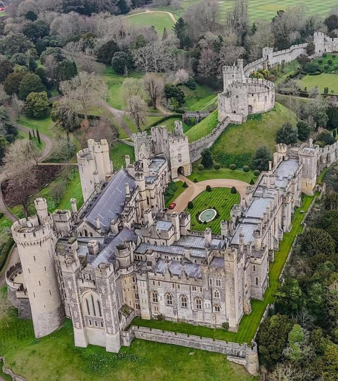 Aerial view of Arundel Castle, UK, with stone towers, battlements, and green gardens