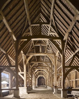 Interior view of historic timber barn showing repeating wooden arch structures and central aisle perspective