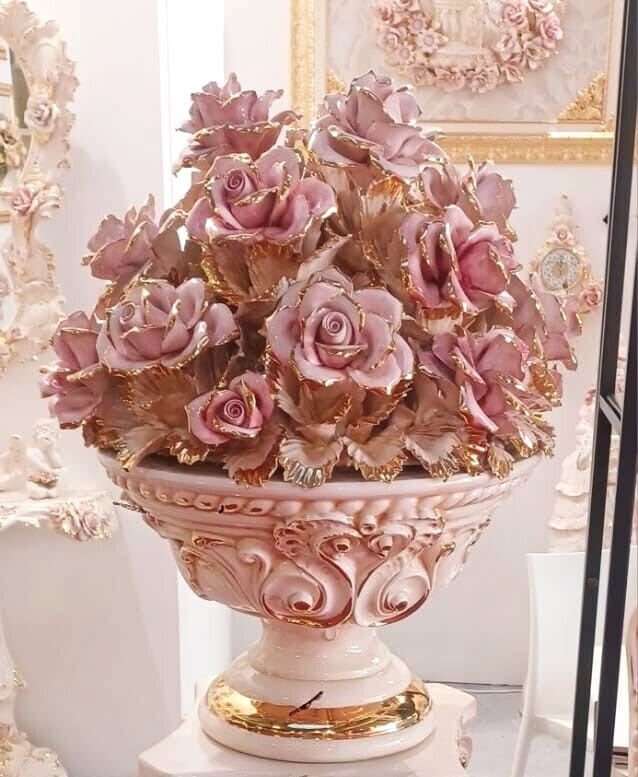 Ornate pink vase filled with pink roses and leaves indoors