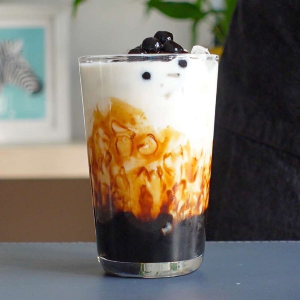 Glass of brown sugar boba milk tea with tapioca pearls and whipped cream