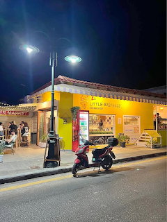 Yellow pizzeria on a street at night with a scooter parked in front