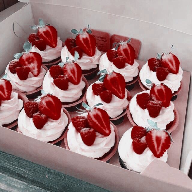 White cupcakes with strawberry topping and blue stars in a pink box