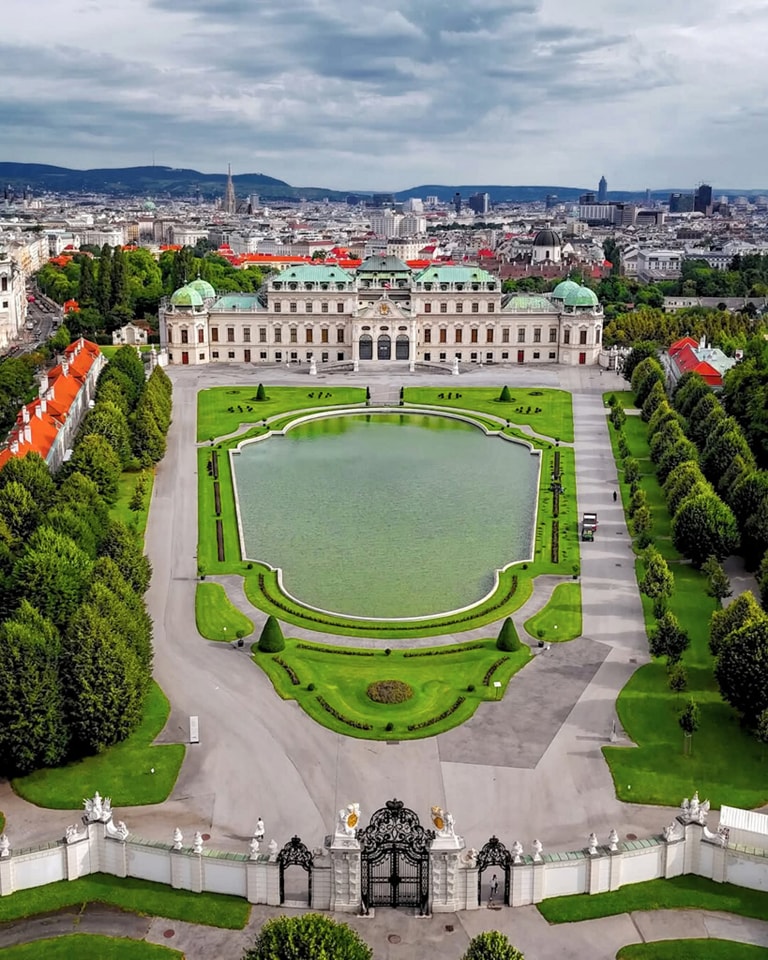 Aerial view of ornate baroque palace with formal gardens and reflecting pool in Vienna