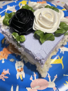 Slice of cake with black and white frosting roses on a blue plate