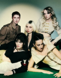 Five women posing together in vintage-style outfits in a moody magazine photoshoot