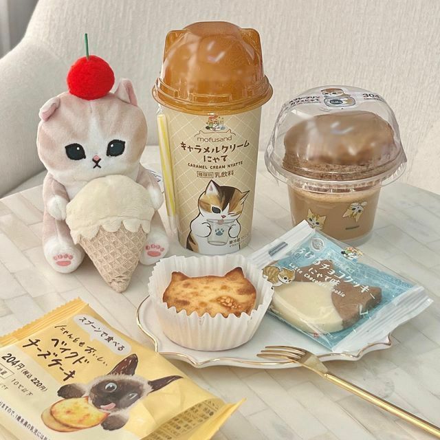 Kawaii dessert flatlay with iced coffee, cookies, pastries and cute cat figurine holding ice cream cone