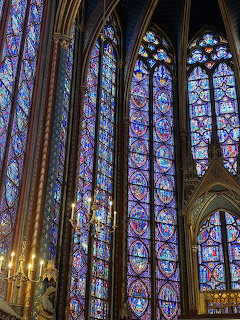 Tall stained glass windows inside a Gothic church with intricate colorful patterns