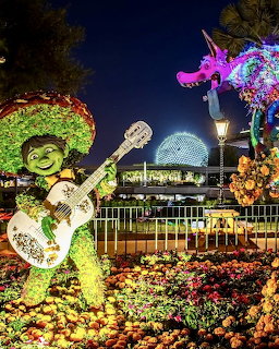 Illuminated floral topiaries at night with geodesic dome in background at theme park