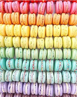 Rainbow gradient of French macarons arranged in neat horizontal rows from pink to purple