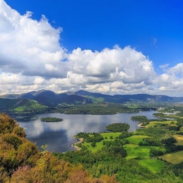 View of Derwentwater Lake District with lake, green fields, hills, and dramatic clouds