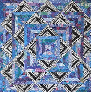 Geometric patchwork quilt with diamond patterns in blue, purple, and polka dot fabrics