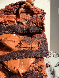 Close-up of stacked chocolate brownies with thick chocolate frosting between layers