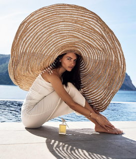Woman in white dress and wide-brim straw hat sitting on waterfront dock