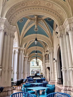 Ornate covered terrace with turquoise arched ceilings, classical columns, and blue chairs