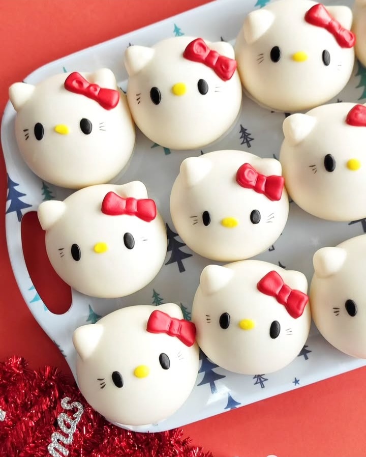 Nine Hello Kitty-themed white round pastries with red bows arranged on a white tray