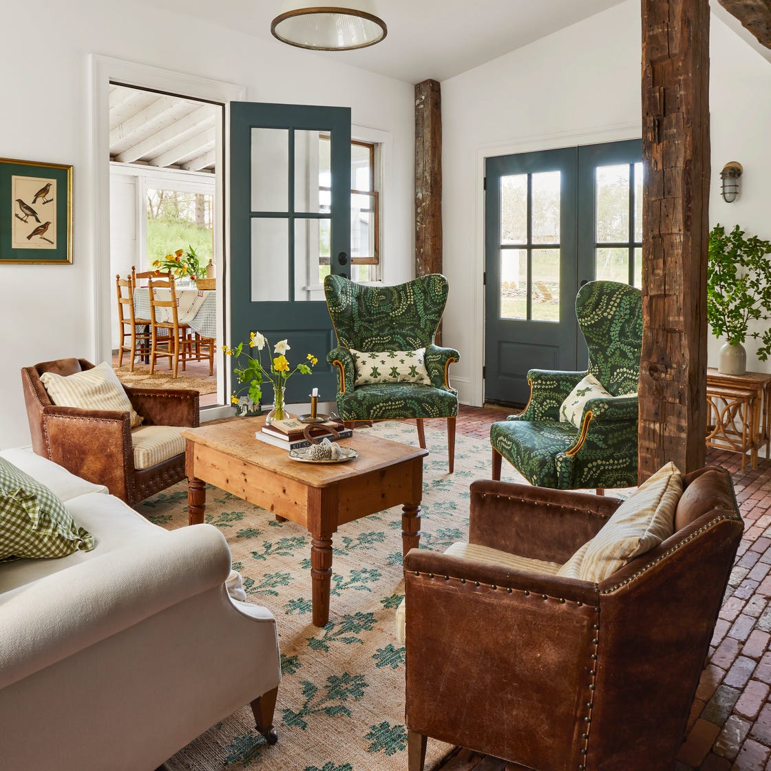 Cozy living room with green paisley chairs, leather armchairs, wooden coffee table, and teal French doors