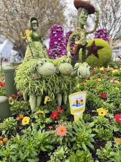 Topiary sculptures of Toy Story characters Woody and Buzz Lightyear made from plants and flowers in a garden setting