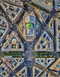 Top-down aerial view of geometric city blocks and streets around a central domed building