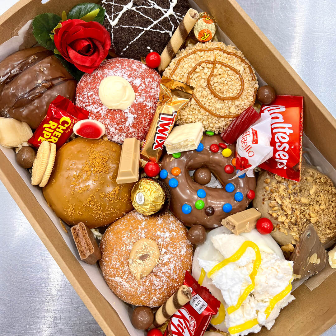 Box of assorted donuts, cookies and candies with various colorful glazes and toppings