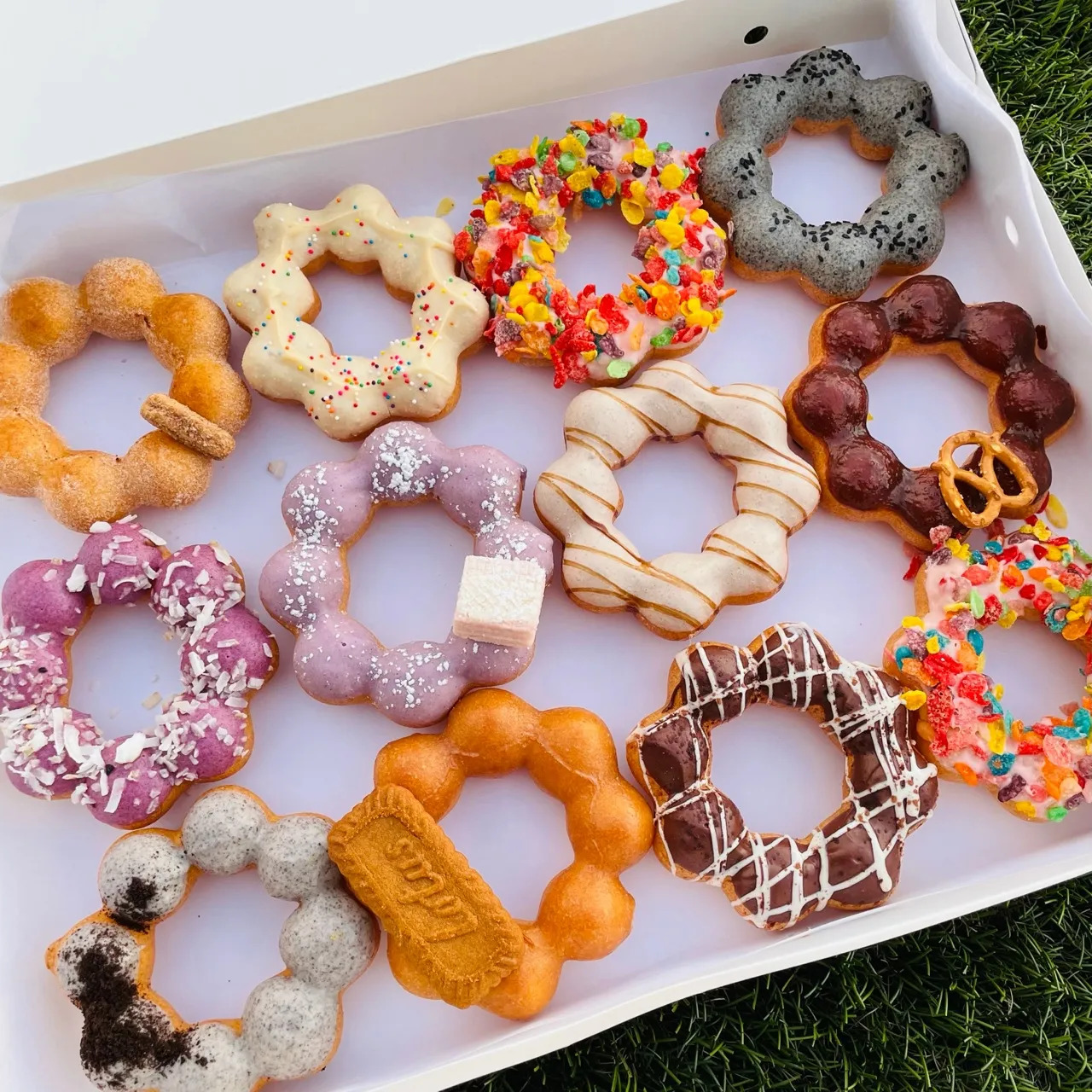 Assorted mochi donuts with various toppings in white box