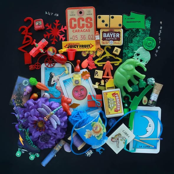 Colorful collage of assorted small objects, toys, cards, flowers, and trinkets on a black background