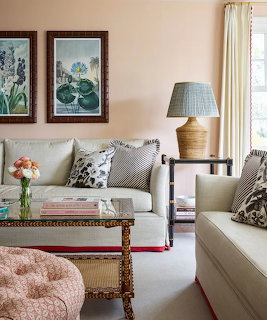 Elegant living room with cream sofa, botanical art prints, glass coffee table, and pink tufted ottoman
