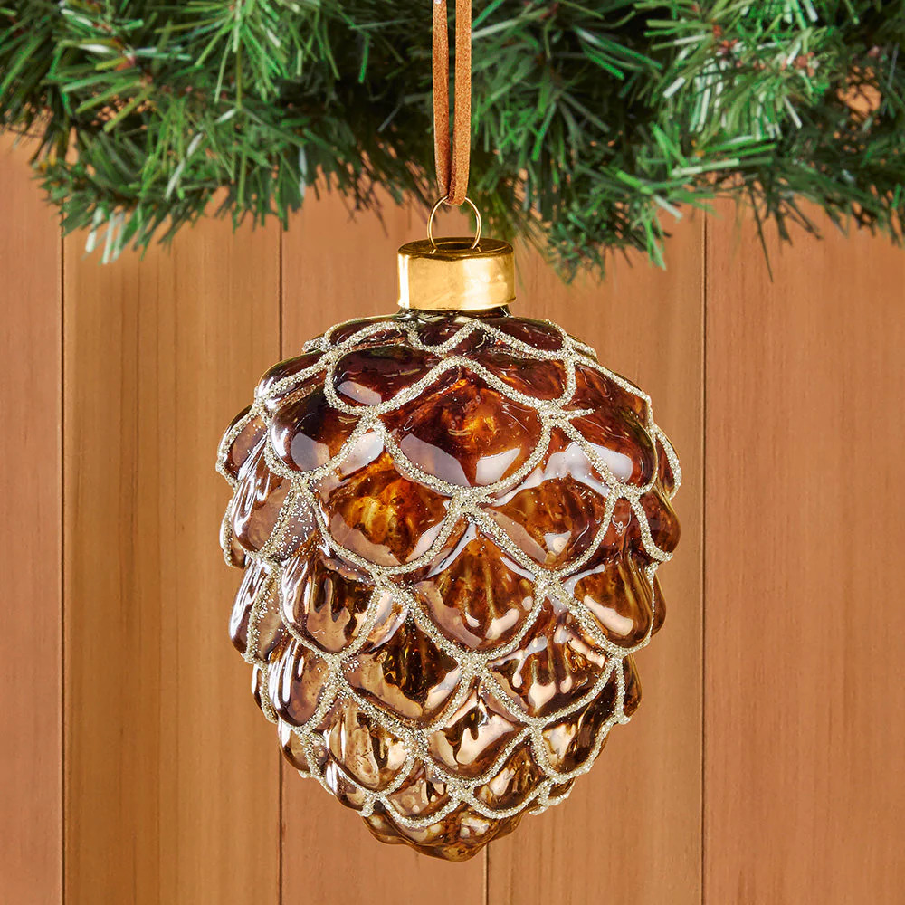 Gold and brown glass pinecone ornament hanging from green pine branch