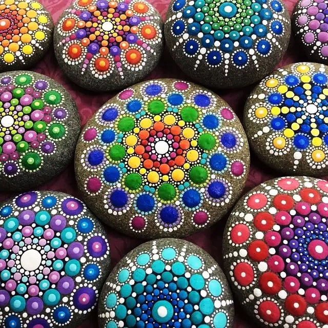 Collection of decorative stones hand-painted with colorful mandala dot patterns in geometric arrangements
