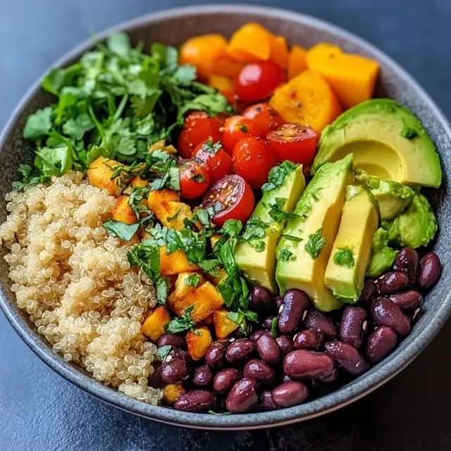 Colorful buddha bowl with quinoa, black beans, avocado, cherry tomatoes, sweet potato, and cilantro
