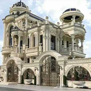 Ornate white baroque palace with twin domes, columns, and decorative ironwork gates