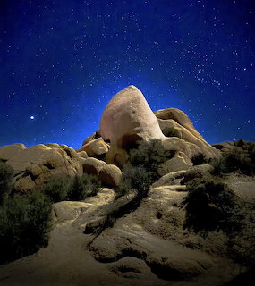 Skull Rock formation at Joshua Tree National Park illuminated under a dark stary night sky