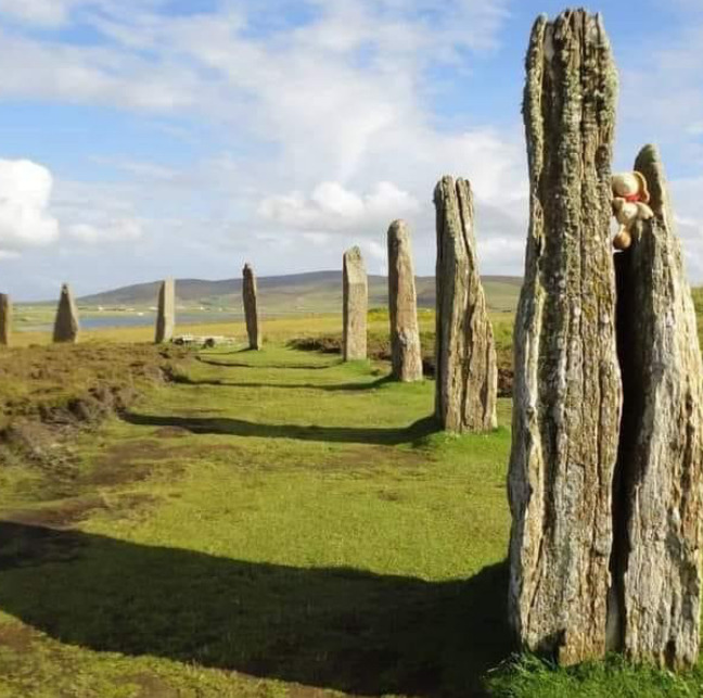 Ancient standing stones in a grassy field beneath a blue sky