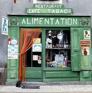 Green vintage Parisian cafe storefront with Restaurant Cafe Tabac signs and classic shutters