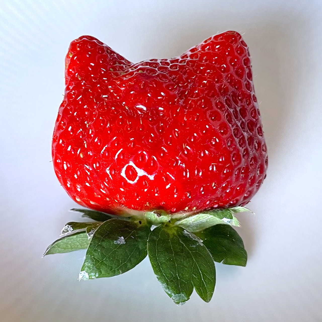 Red strawberry carved into Hello Kitty cat shape with green leaves