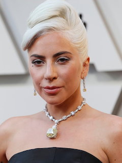 Blonde woman in a black strapless dress wearing a diamond necklace and earrings