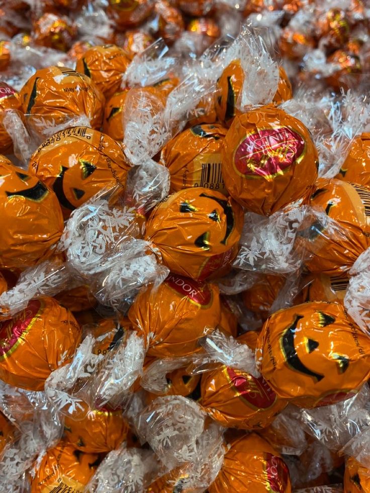 Pile of orange pumpkin-shaped wrapped Halloween chocolates in clear cellophane