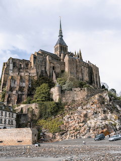 Stone castle and abbey on a rocky hill beneath a cloudy sky