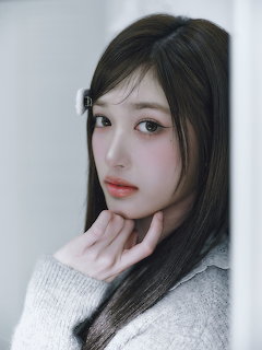 Young Korean woman with long dark hair in gray knit sweater posing with hands under chin