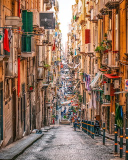 Narrow cobblestone street in Naples with colorful buildings and hanging laundry