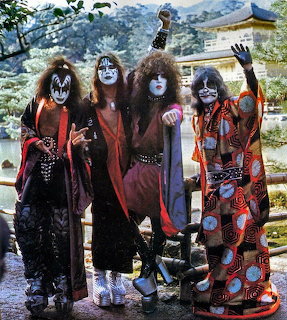 Four KISS band members in makeup and costumes posing in a Japanese garden